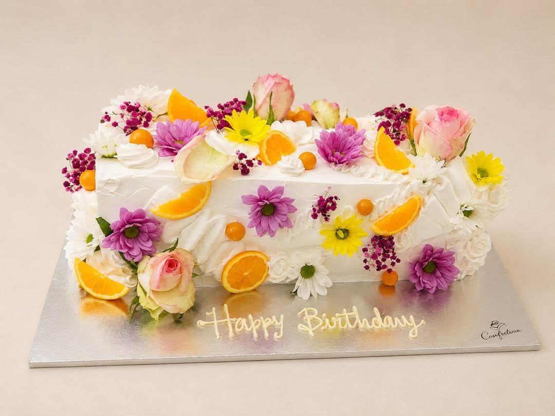 Bolo retangular decorado com flores comestíveis e a mensagem Happy Birthday