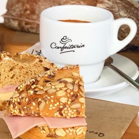 Chávena de café da Confeitaria com uma fatia de bolo de amêndoa