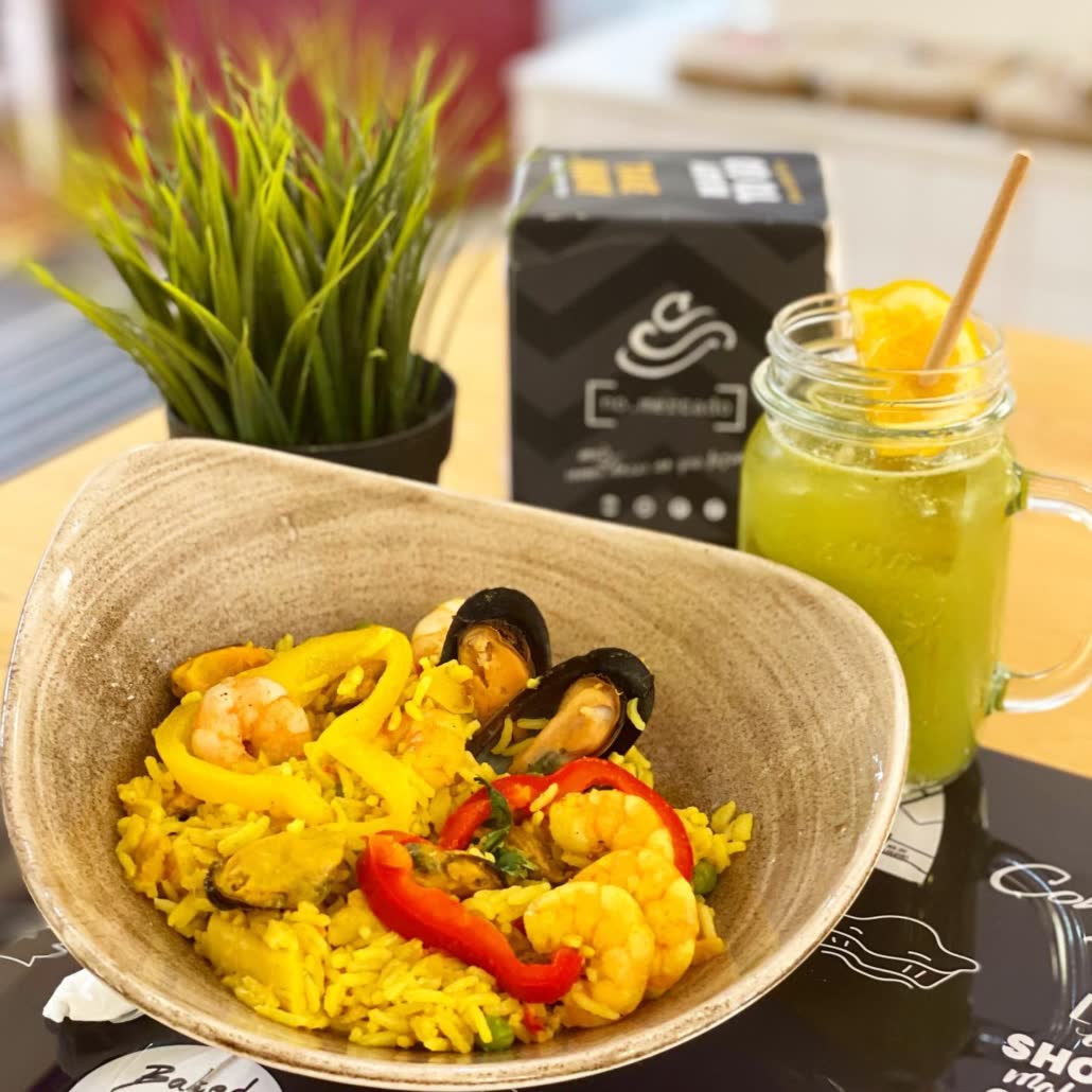 Prato de arroz com legumes e sumo natural numa mesa da Confeitaria